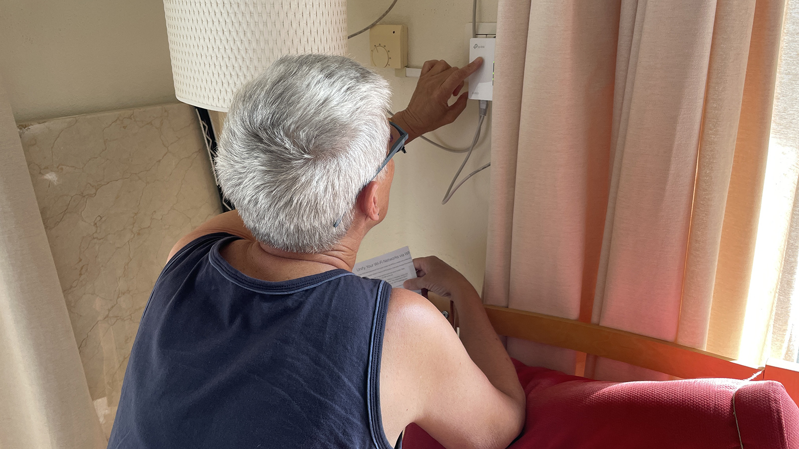 Petra installeert het apparaat dat ervoor zorgt dat we via het stroomnet ook internet in het kleine huis hebben